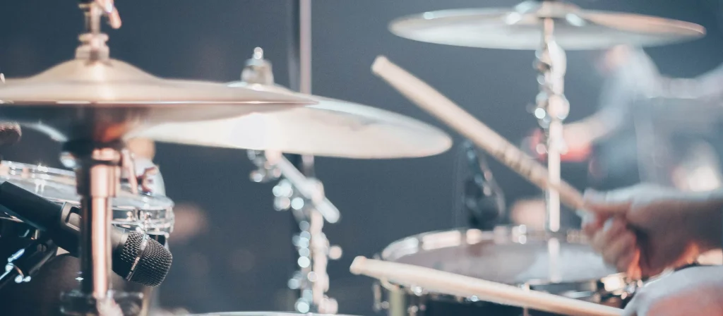 Drummer playing a drum kit on stage with cymbals and a snare microphone