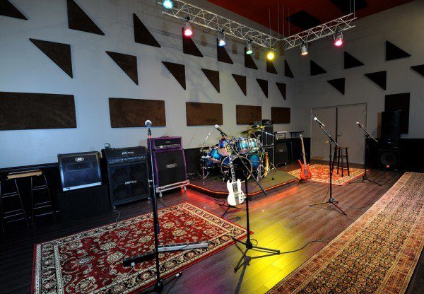 Rehearsal and live room with drum riser, amplifiers, stage lighting and acoustic panels